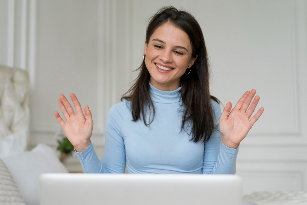 Chica sentada en el sofá, saludando al laptop